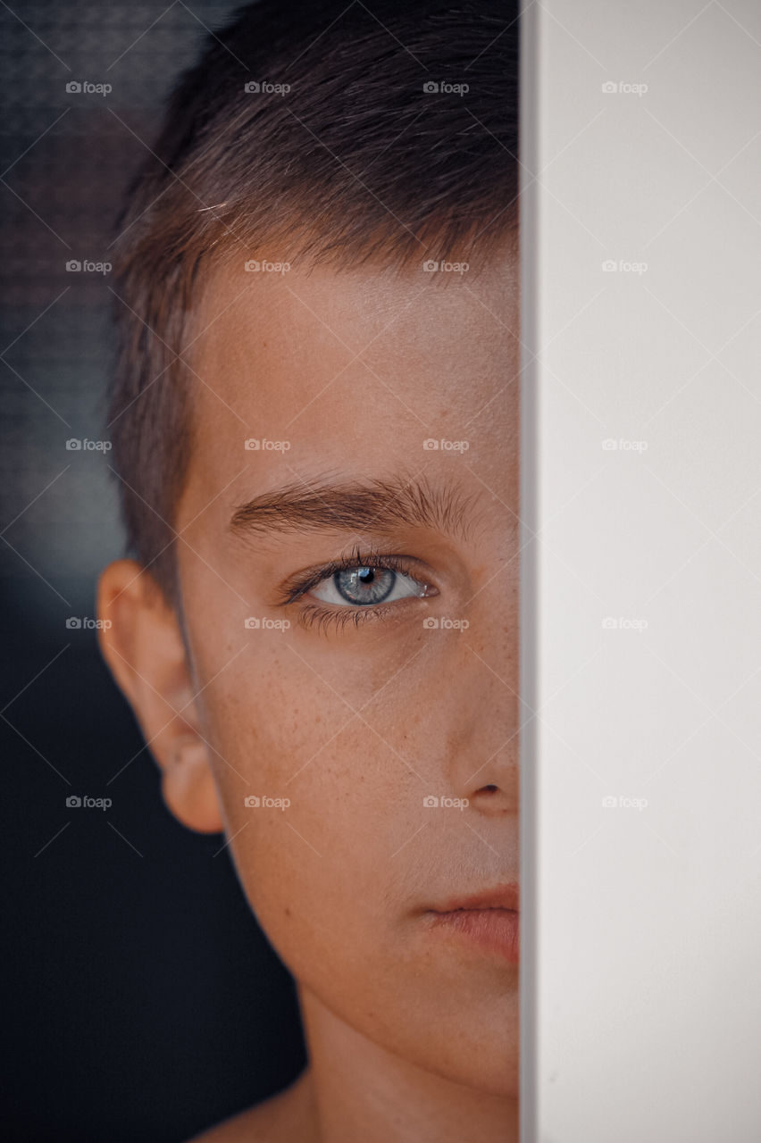 Close-up portrait of littel boy behind the window frame