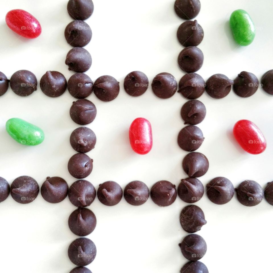 Tic-tac-toe with chocolate chips and green and red jellybeans