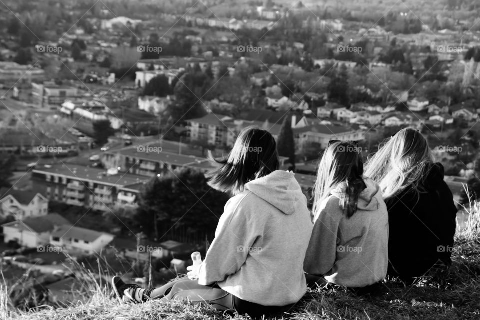 Friends sitting on a hill above the city on a sunset 