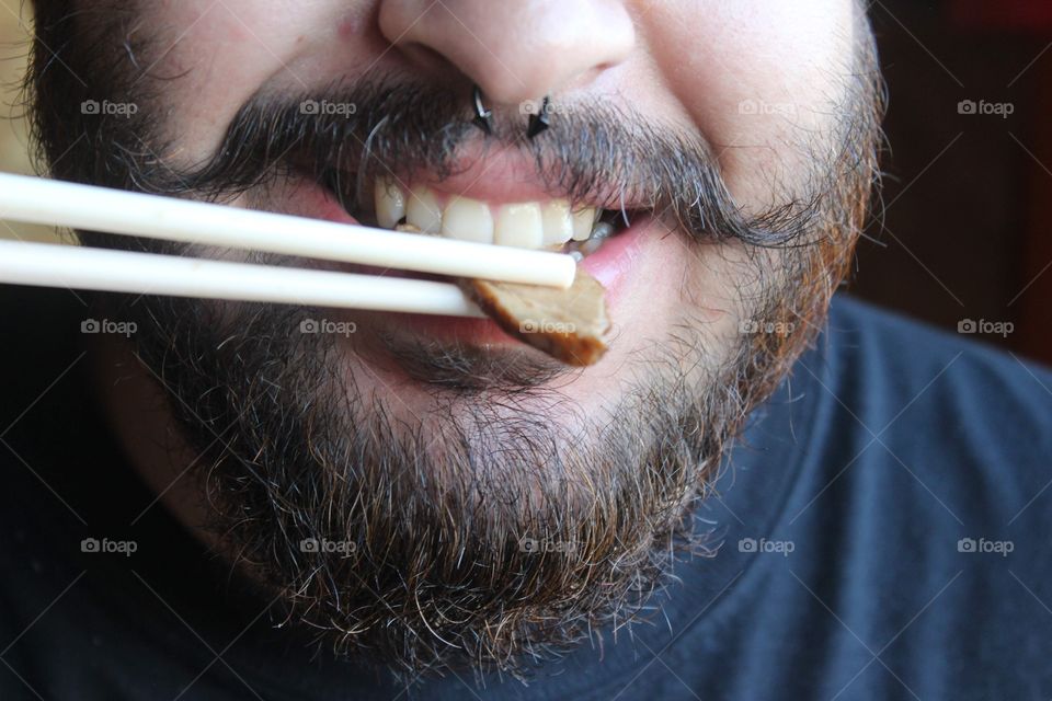 Beard man eating with chopsticks 