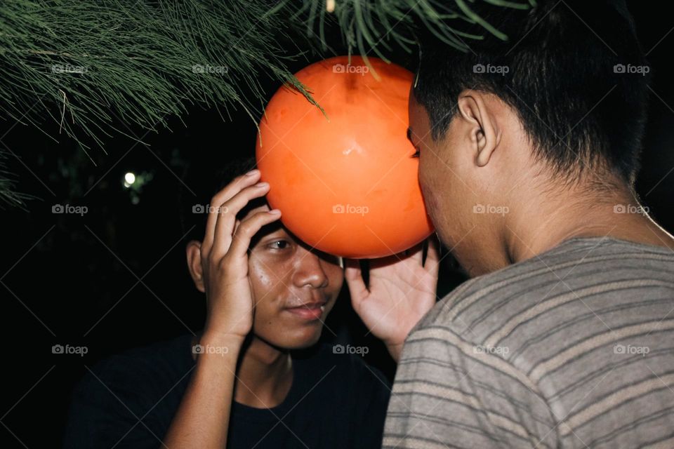 Close up of a group of men looking happy doing a dance game with balloons attached to their heads, a teamwork game to build a great team.