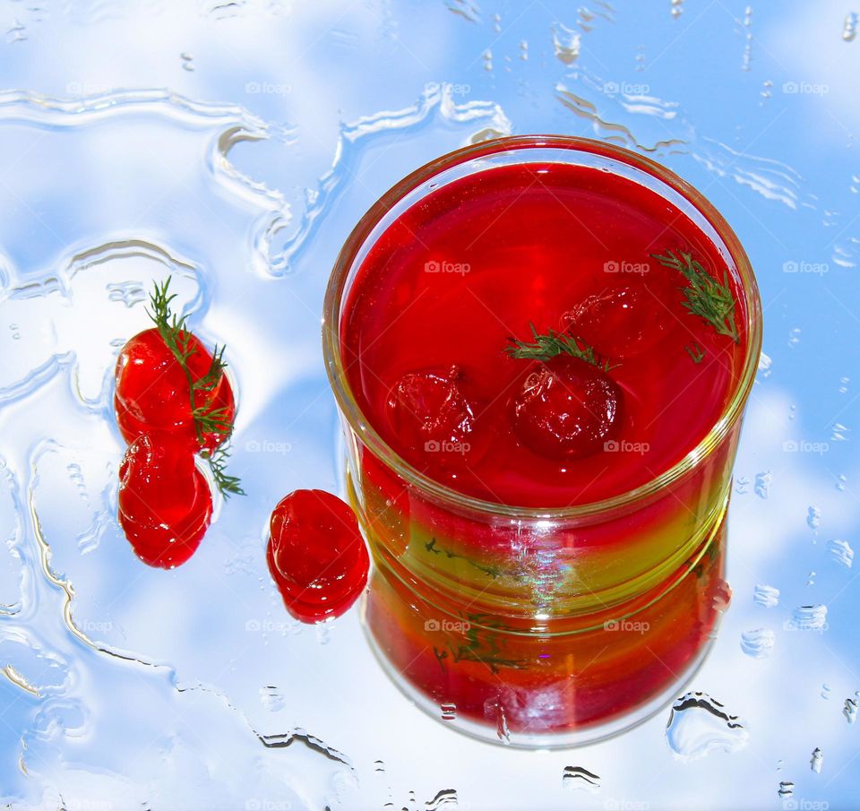 Fruit jelly with cherries in a glass on a background with the reflection of the sky