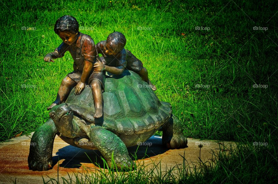 Vibrant photo of a statue portraying children playing on a turtle.