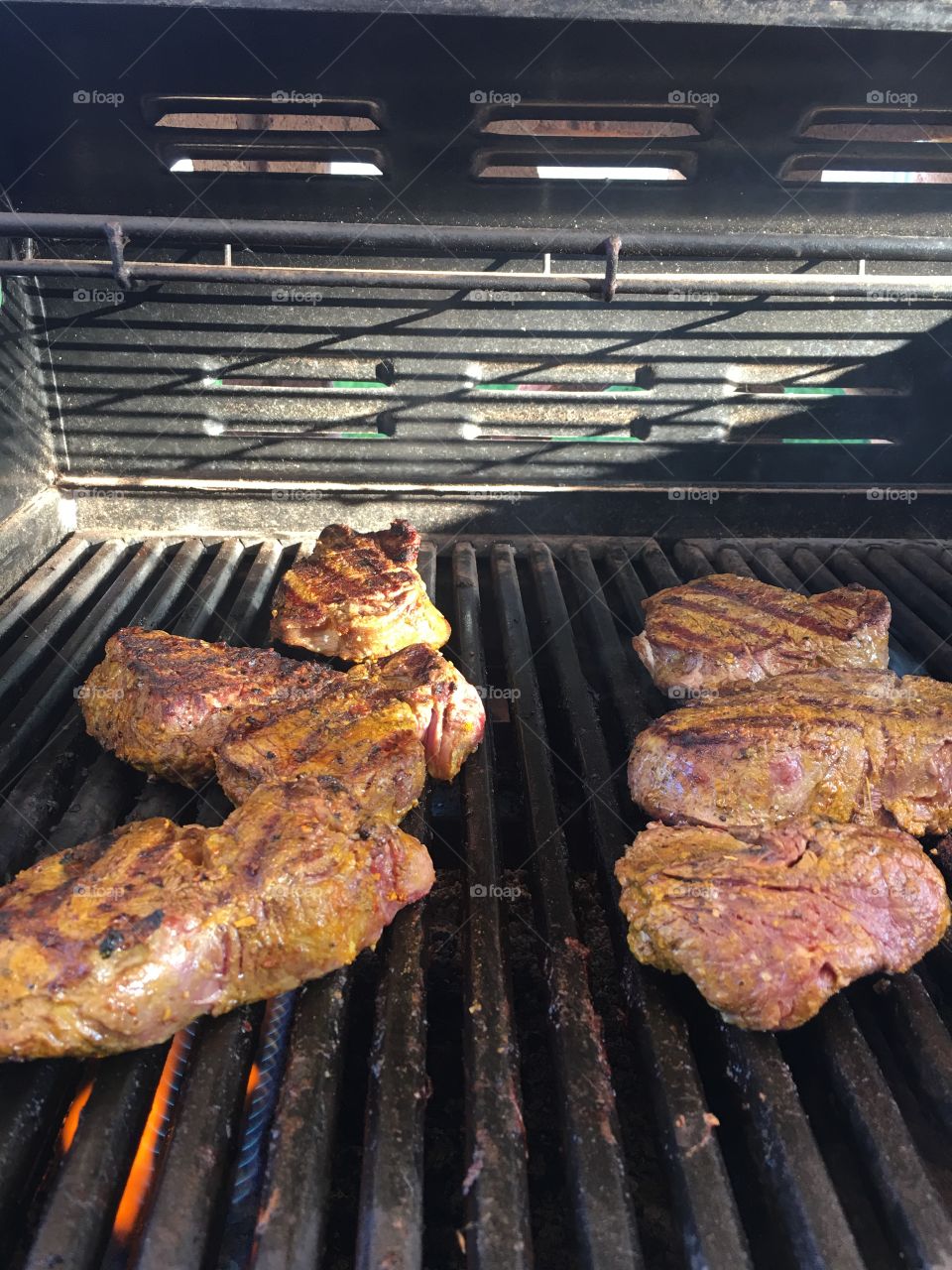 Four beef steaks on the barbie barbecue BBQ