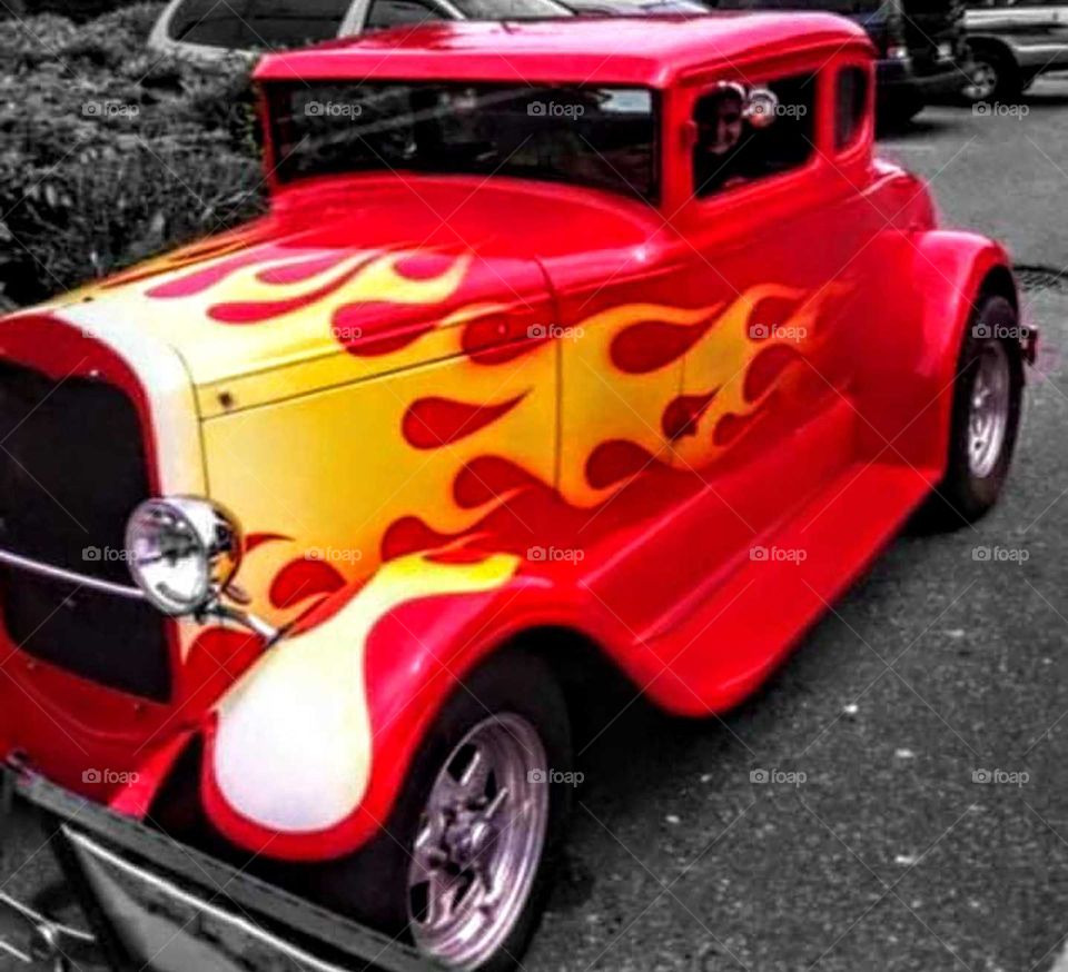 Photograph of red and yellow hotrod with black and white background