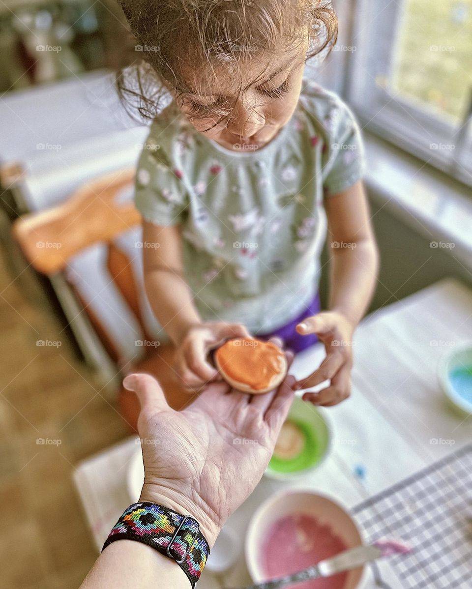 Mother handing little girl an Easter sugar cookie, mother and toddler make holiday cookies together, making memories in the kitchen, love through baking, Easter traditions 