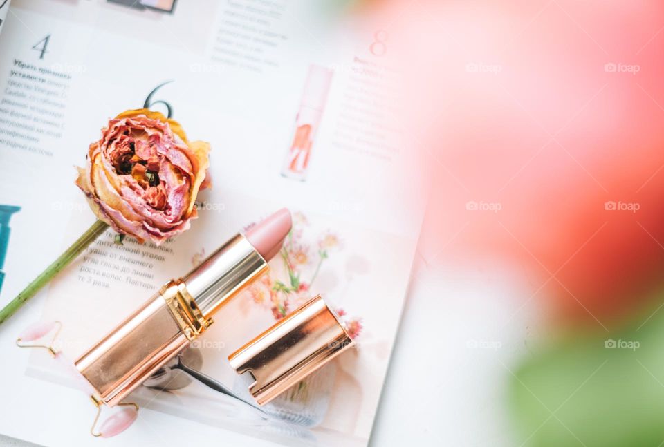 Pink lipstick cosmic product flat lay on magazine 