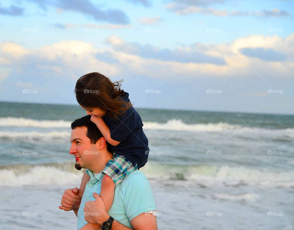 Father & son on beach. This daddy gives his little toddler a piggyback on the beach