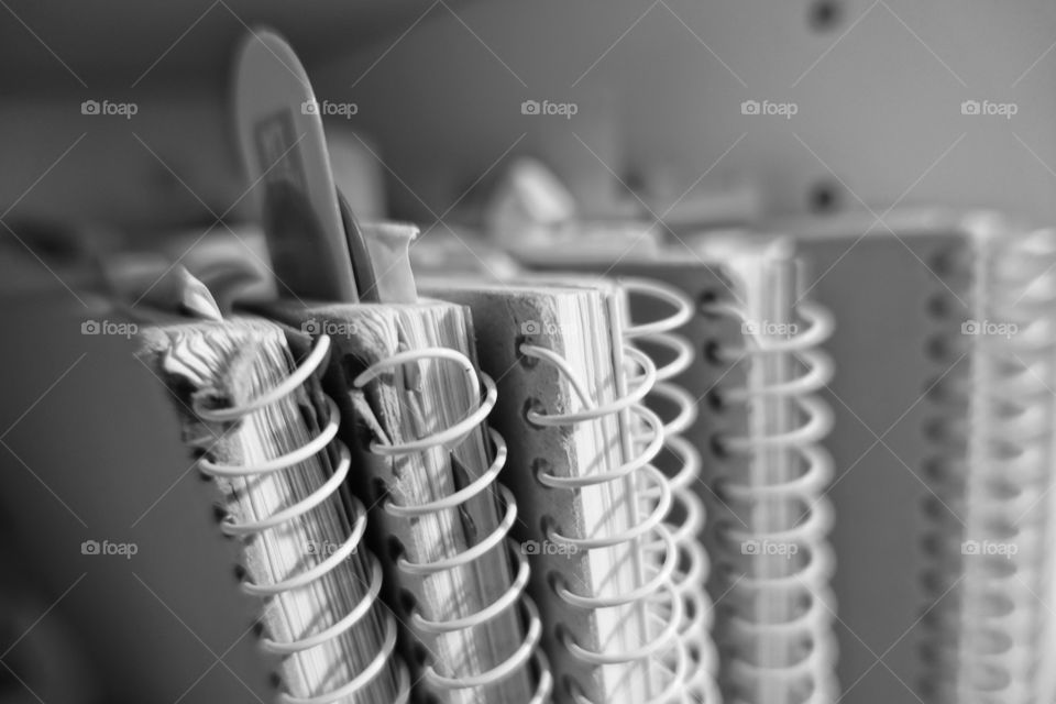 Notebooks on the bookshelf. Monochrome image.
