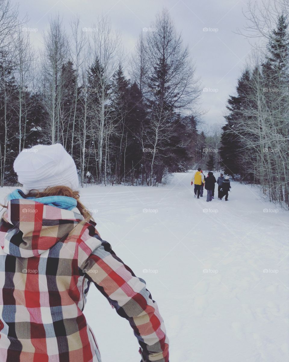 Girl and friends walking in the winter into a forest