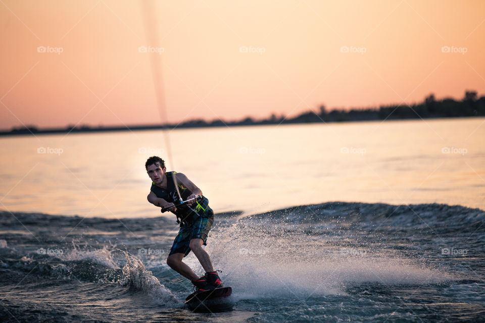 Man wakeboarding on sea at sunset