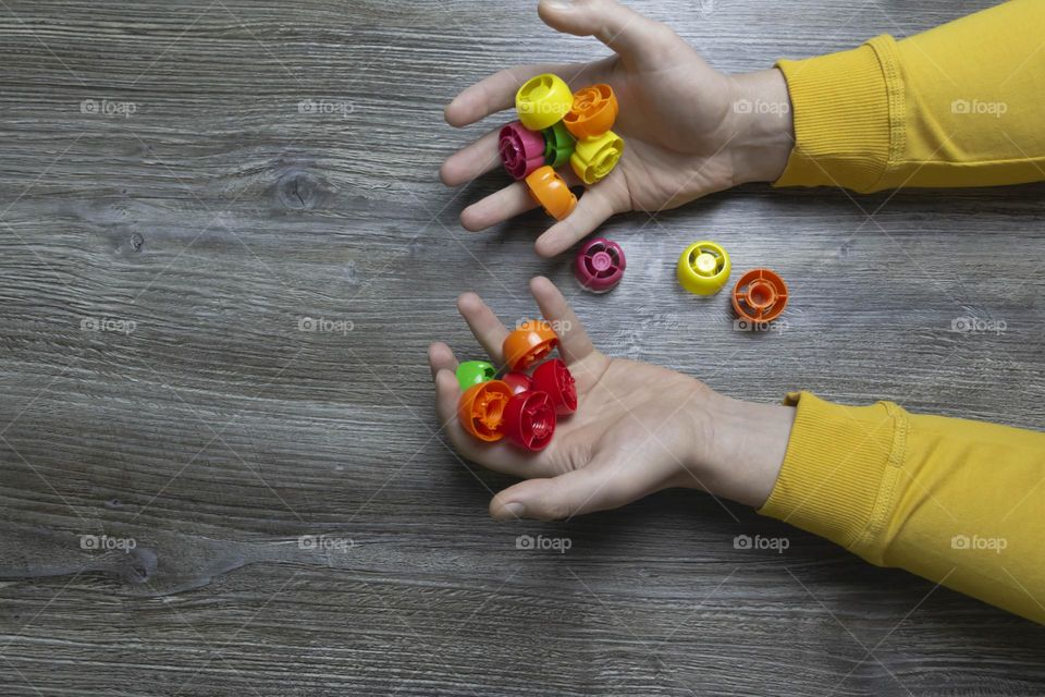 We collect garbage, plastic plugs and plastic to save our planet, nature and the environment. Men's hands lie on a gray wooden surface, which is used as a background or a surface with incident light.