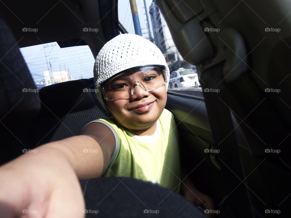 young boy wearing a bonnet inside a car