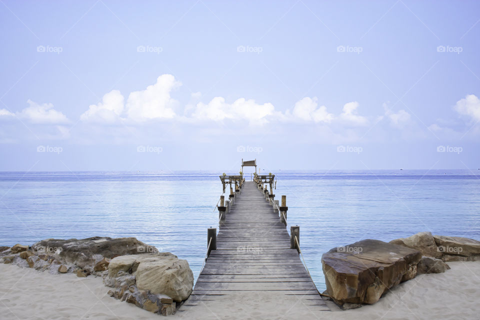 Wooden bridge pier boat in the sea and the bright sky at Koh Kood, Trat in Thailand.