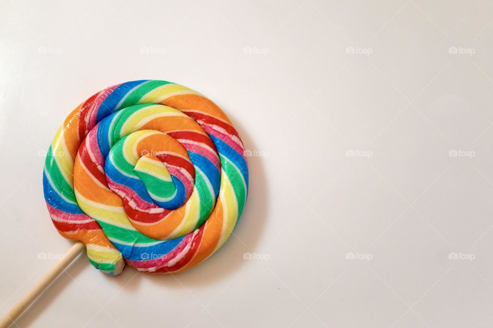 Rainbow colored lolly on a white background