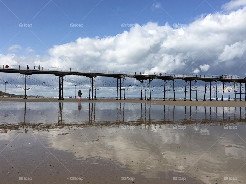 Clouds at the beach in the sky and reflecting on the low tide water 