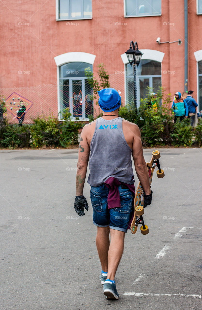 Man is walking down the street with skateboard in his hand 