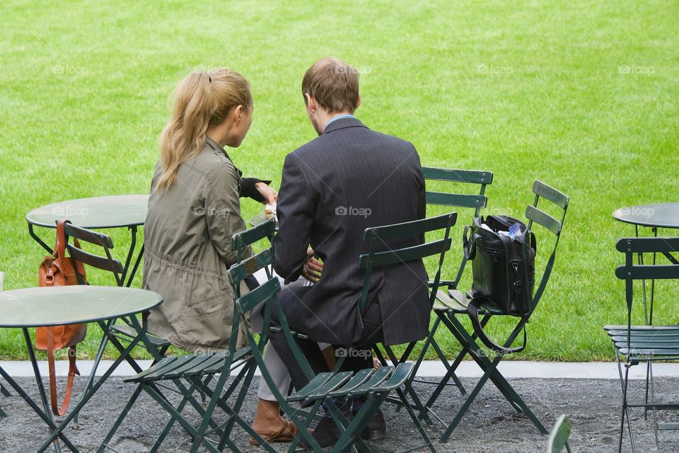 A rear view of a businesswoman and a businessman meeting in a public park in Manhattan, New York City,.