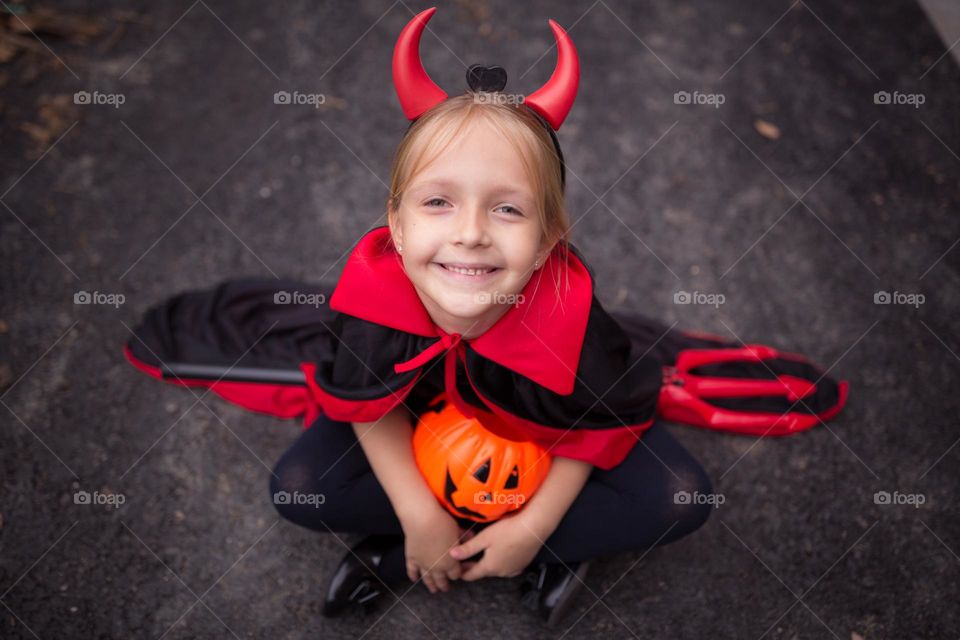 Happy girl in devil costume celebrating Halloween 
