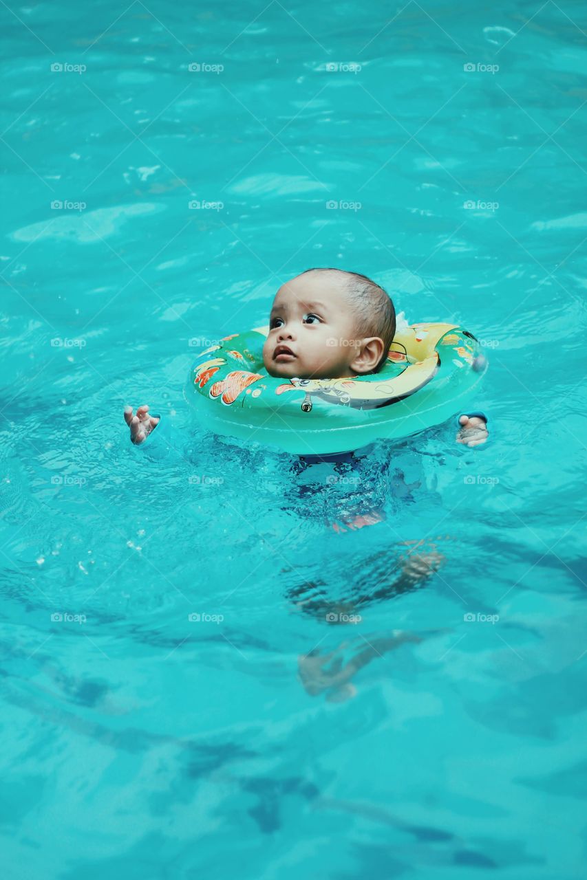Baby boy swimming in the pool.