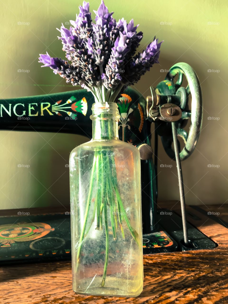 Lavender floral Bouquet in an antique bottle sitting on an antique Singer Treadle sewing machine