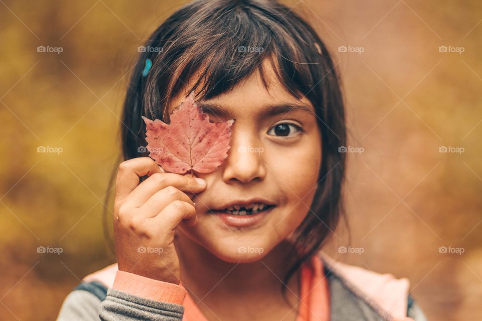 Cute little girl with an autumn leaf