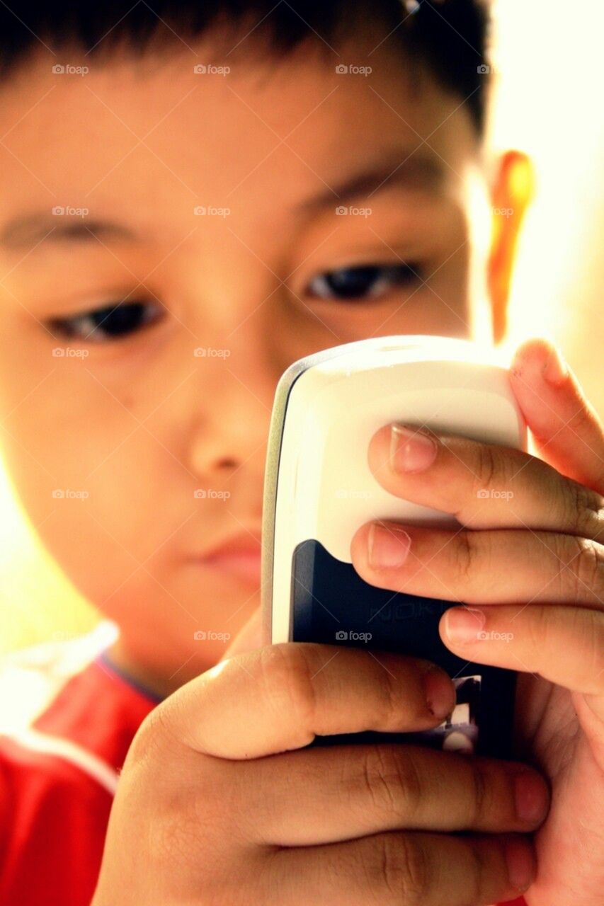 Little boy learning to operate an old cellphone