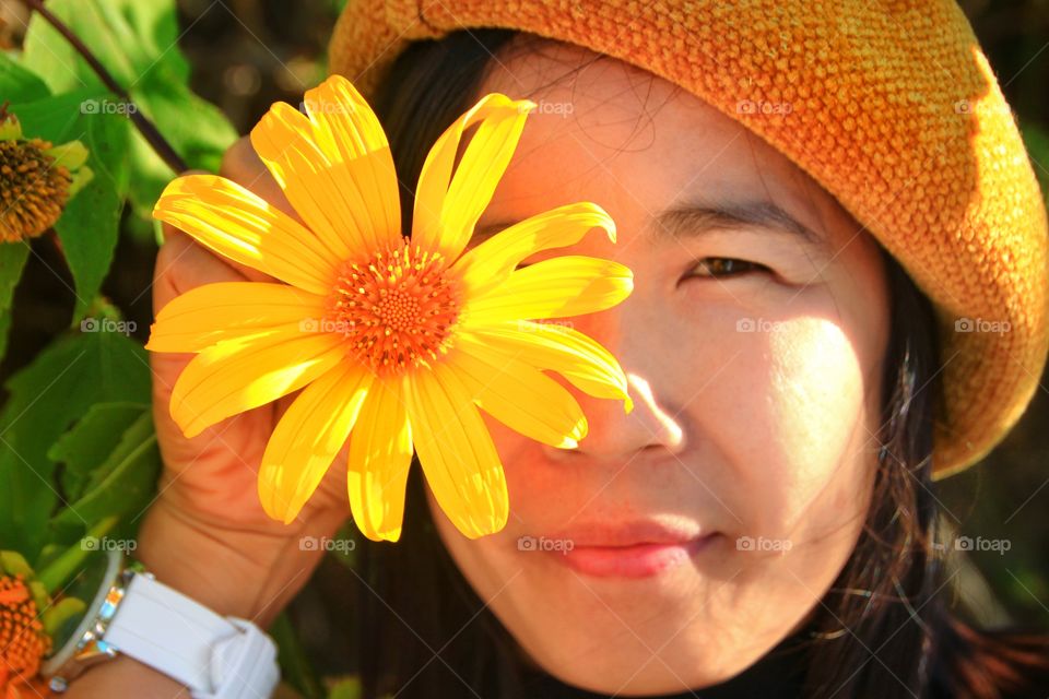 Photos of lovely women with beautiful yellow flowers blooming seasonally. The eyes from a lovely woman and the other eye from a blooming yellow flower.