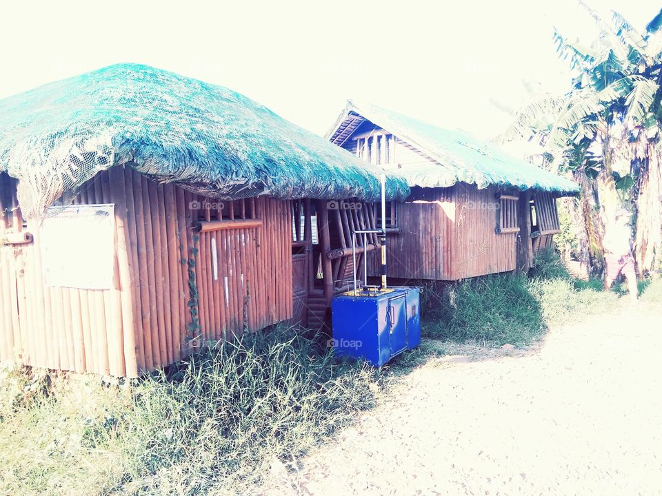 Two Nipa hut houses with fish ball vendor's cart.