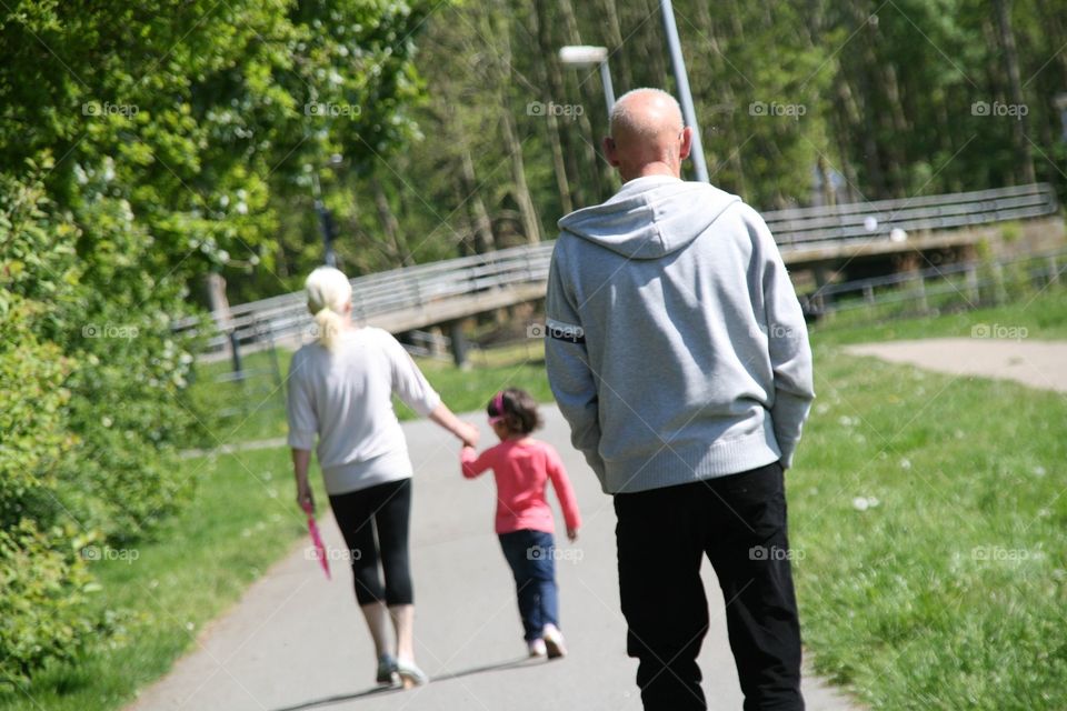 Grandma and grandpa walking trough the park with their granddaughter 