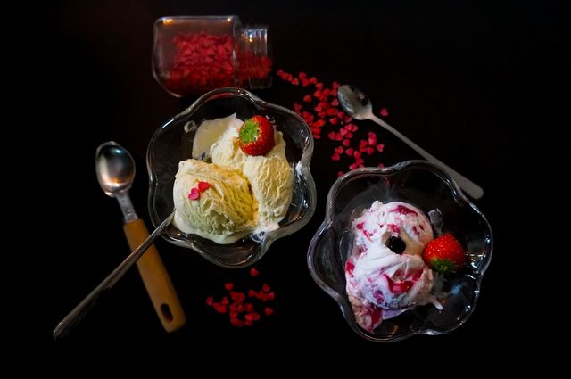 Ice cream on the table with a black background. Flat lay with forest fruit yoghurt and vanilla ice cream