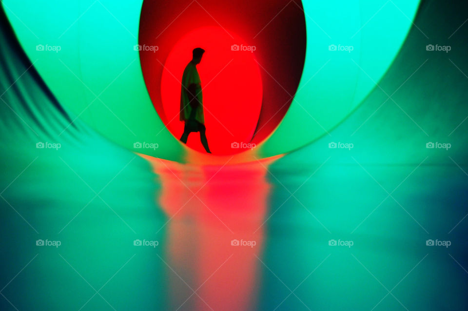 Shadowed figure walking through a maze of color