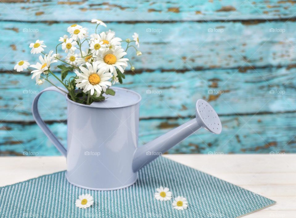 a bouquet of daisies in a watering can