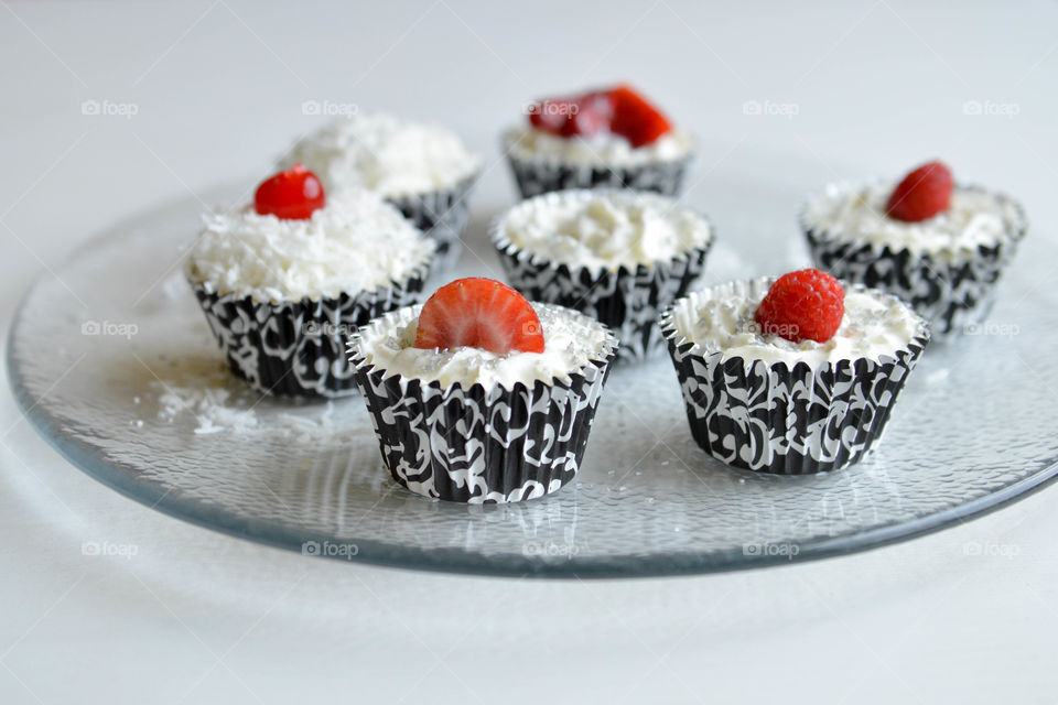 Plate of decorated cupcakes topped with fruit