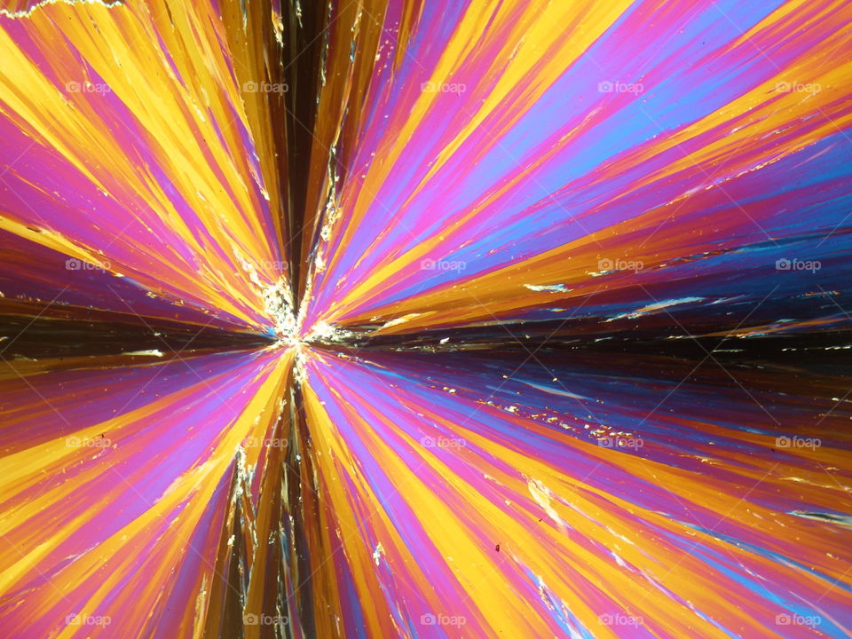 Crystallized liquid crystal under polarized light microscope forming colorful flower.