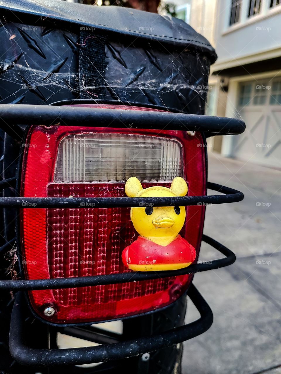 Yellow rubber duck stuck in the safety guard on a vehicle in the streets of San Francisco, going for a ride through this famous city
