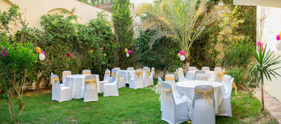 tables and chairs in a garden with decorations and balloons ready for a party