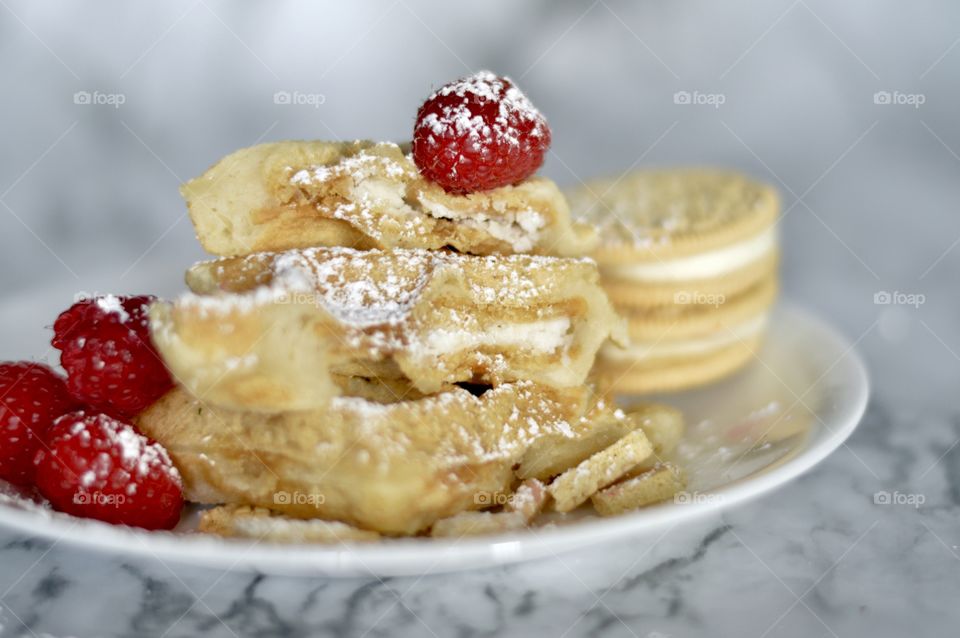 Golden double stuff Oreo cookies and a waffle with raspberries and powdered sugar