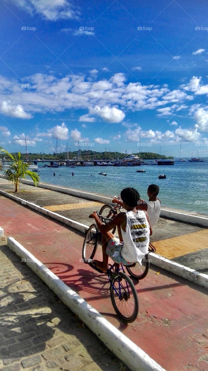Children on bicycle on pathways against sea 