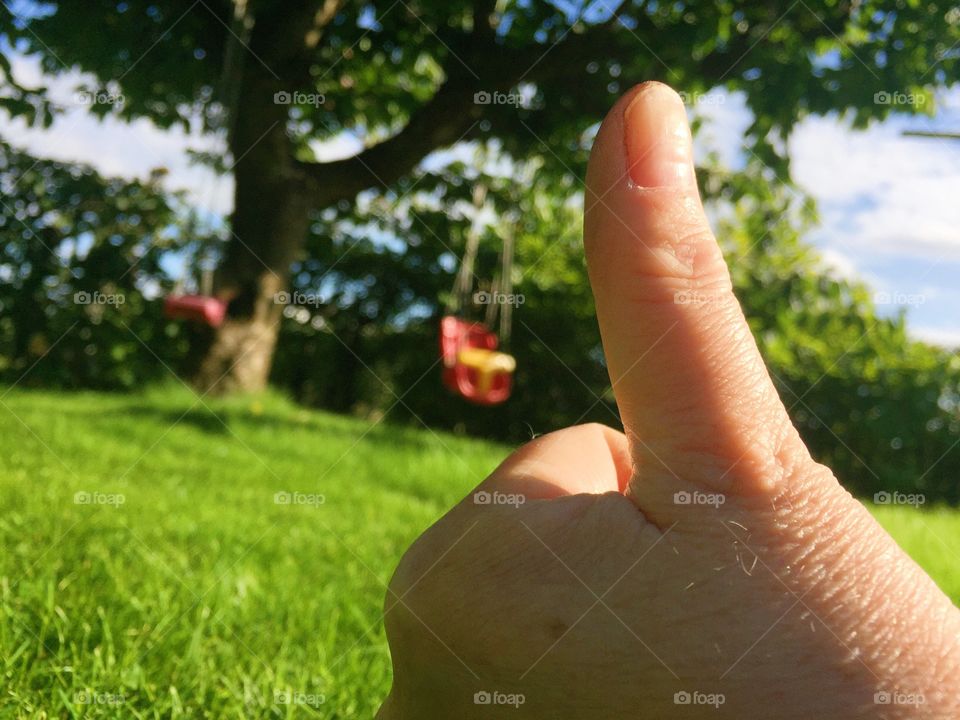 Thumb up in the garden close to the lawn 