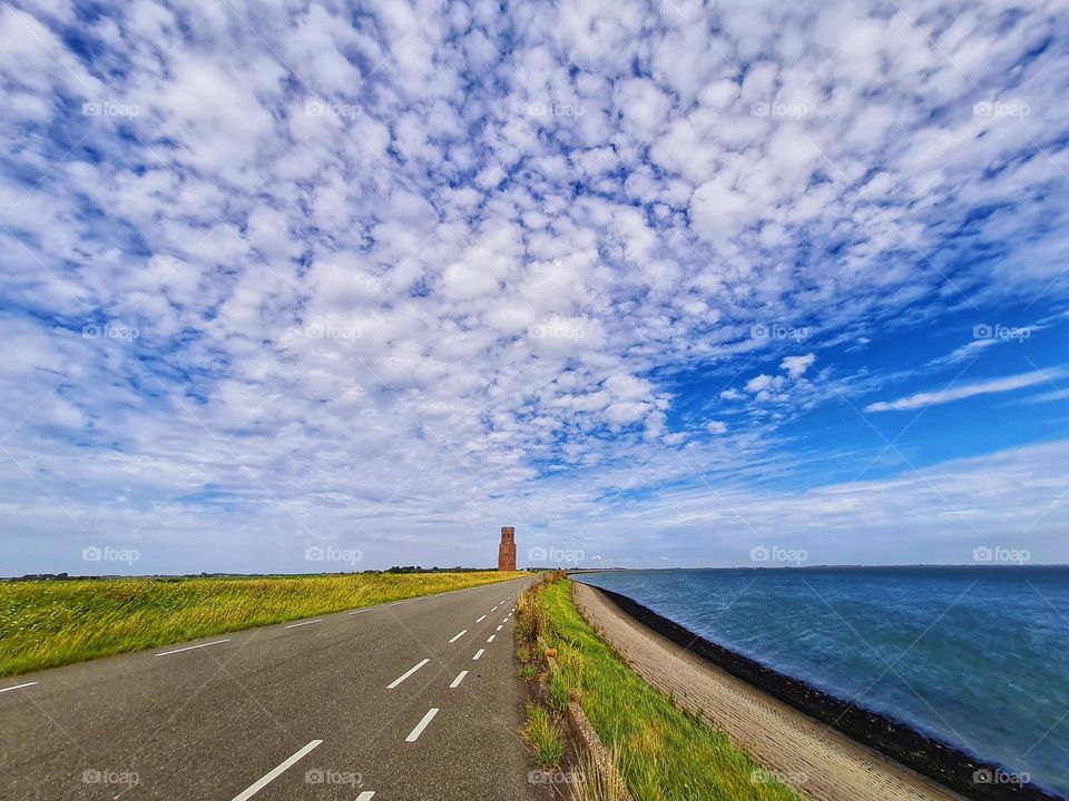 The road near the sea to the bridge in sealand with a view on the plump tower in The Netherland