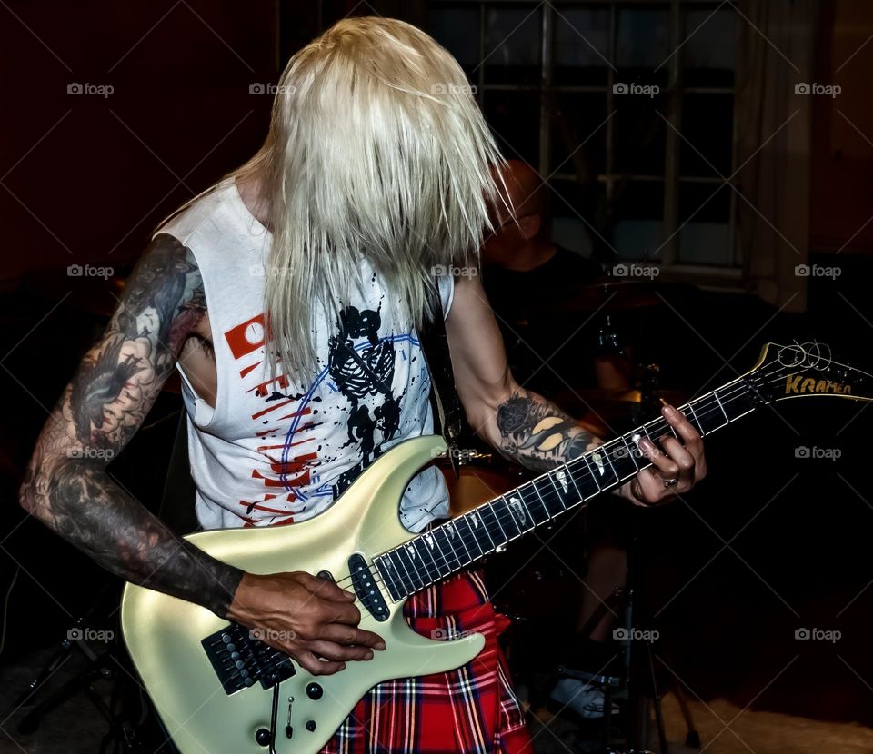 Tattooed punk with blonde hair & tattoos plays guitar