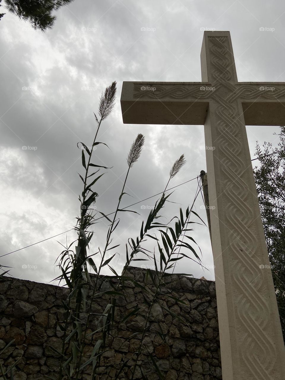 Stone cross against cloudy sky.