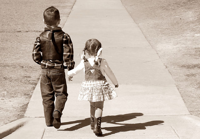Big brother helping little sister across the street to the playground