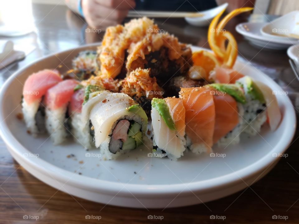 yummy plate of sushi with colorful rainbow roll and tasty volcano roll behind it