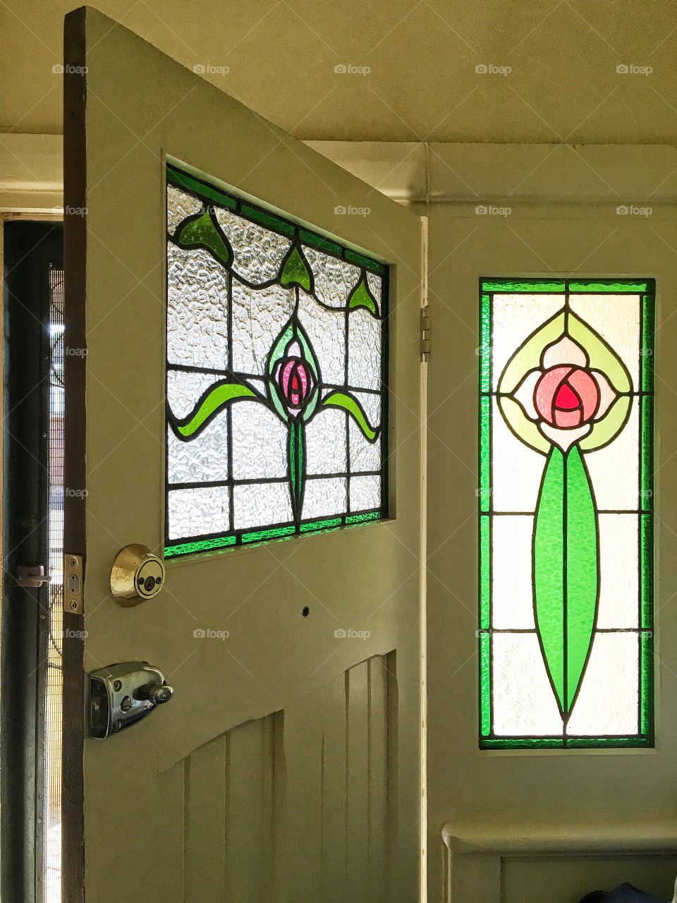 Green stained glass front door and windows captured indoors looking out