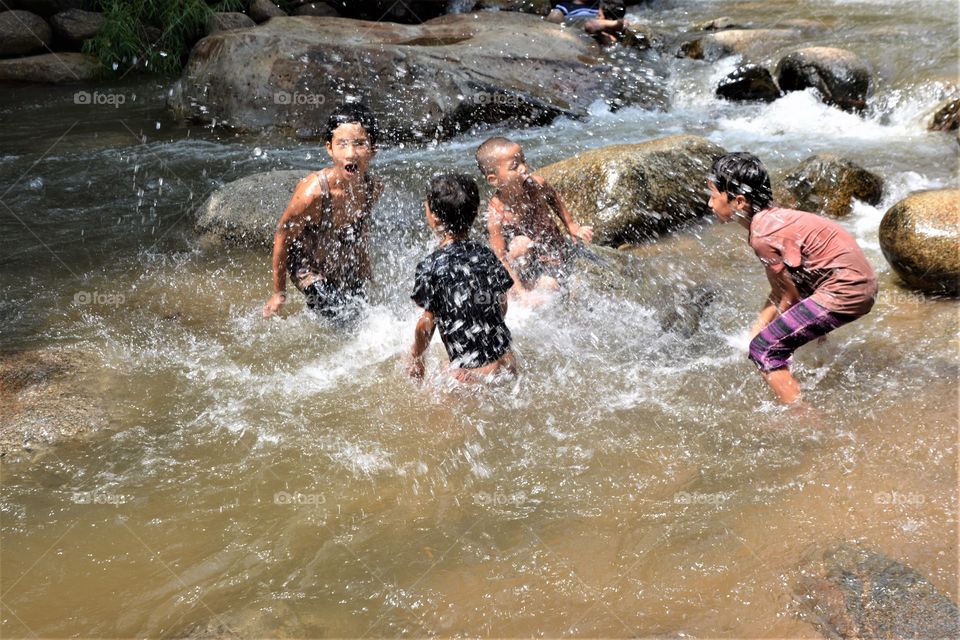 Boys playing water in the stream