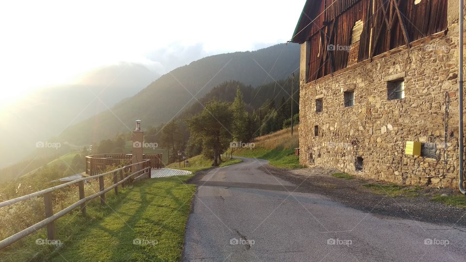 Mountain road with barn in sunset