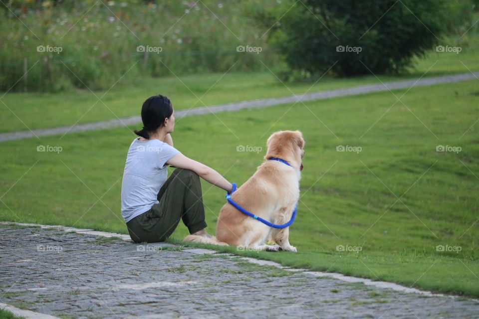 A Women and Her Dog Sitting on A Road and Watching Greenery