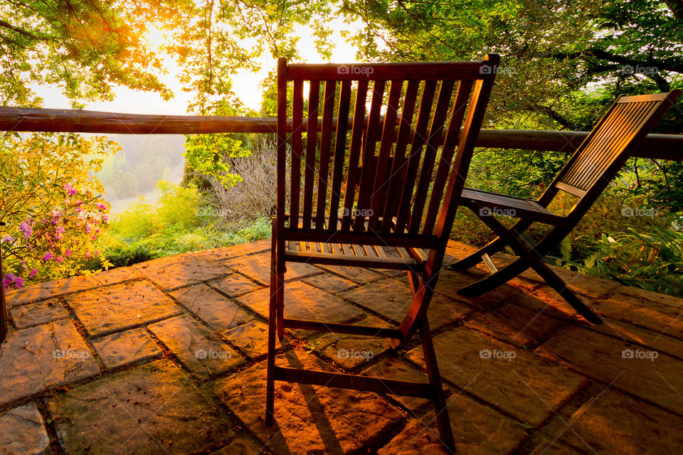 Sunrise over the patio with two wooden chairs overlooking the beautiful valley below